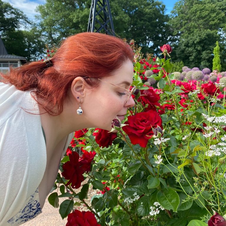 Visitor smelling a deep red rose in the Rose Garden