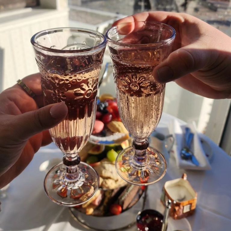 Glasses of sparkling rose cheers together over afternoon tea at the teahous