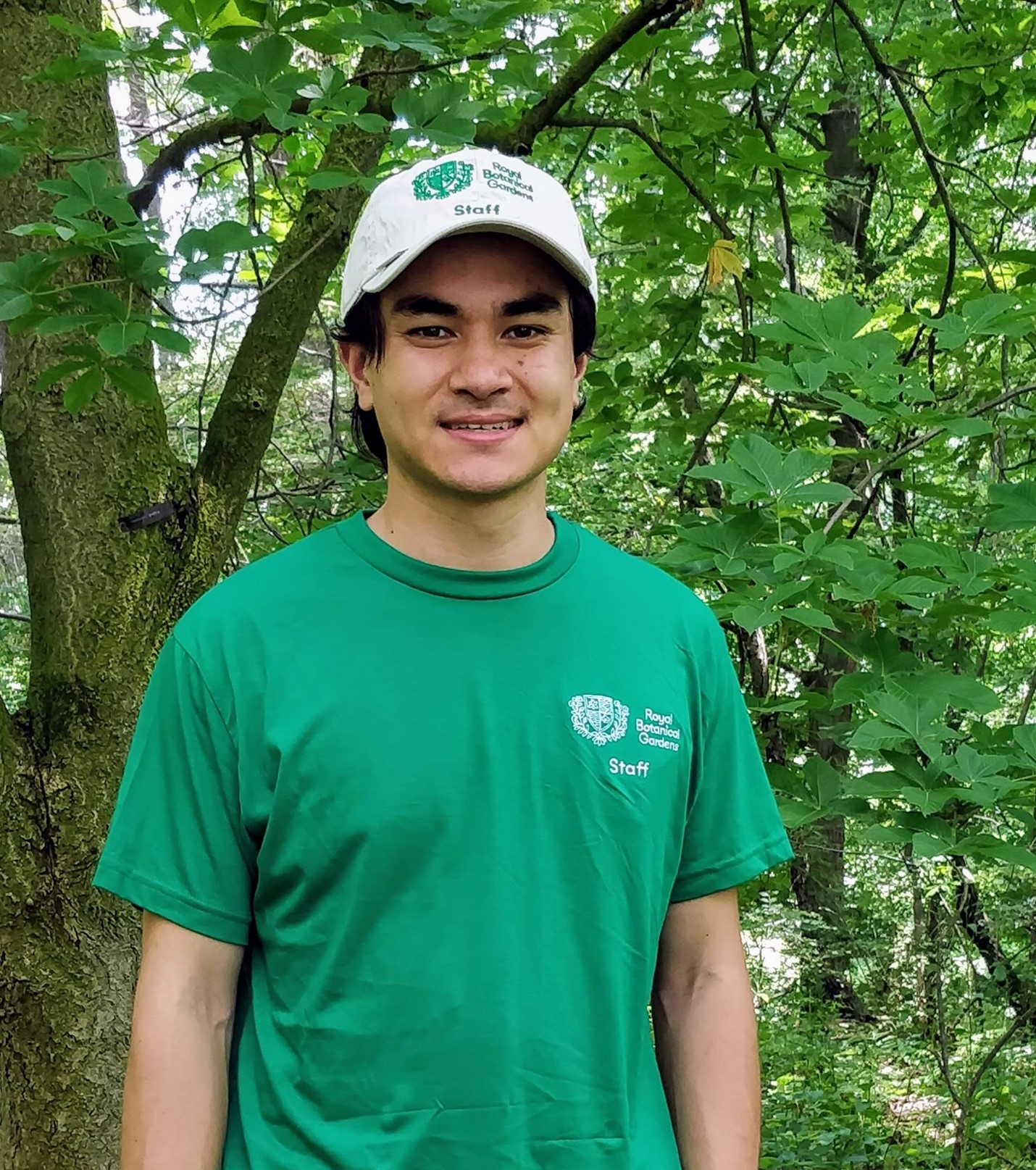 justin chen standing by a tree in the arboretum