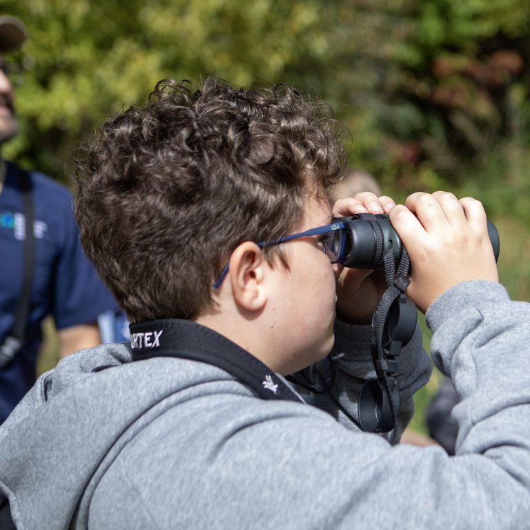 older child looking through binoculars on the nature trail