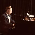 sean stanley sitting and playing a grand piano